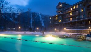 a swimming pool in the snow in front of a building at 347 Lodge At Spruce Peak Ski In Ski In Ski Out King Studio By Stowe Mountain Rentals in Stowe