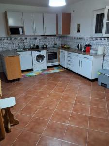 a kitchen with white appliances and a tile floor at Maresia BIKE ROOMS in São Félix da Marinha