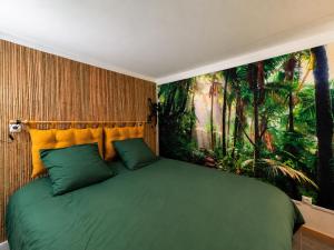 a bedroom with a green bed with a painting on the wall at La Jungle du Vernet, Ambiance Tropicale in Le Vernet