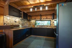 a kitchen with black cabinets and wooden ceilings at Alpas forest house in Kuršumlija