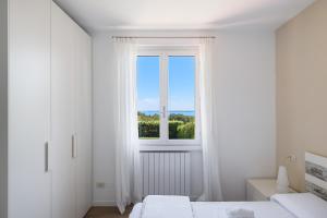 a white bedroom with two beds and a window at Borgo Stropea by Whale Homes in Soiano del Lago +29 photos