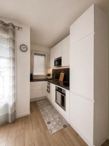 a kitchen with white cabinets and a clock on the wall at Civico 8 in Bollate