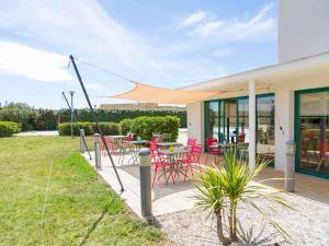 a patio with red chairs and a table on it at ibis Perpignan Nord Rivesaltes in Rivesaltes