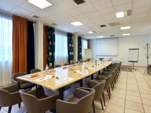 ein großer Konferenzraum mit einem langen Tisch und Stühlen in der Unterkunft ibis Annemasse-Genève in Ambilly