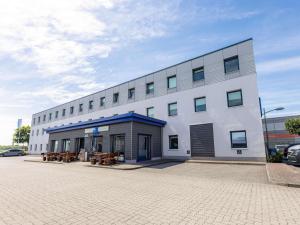 a large white building with benches in a parking lot at ibis budget Flensburg Handewitt in Handewitt
