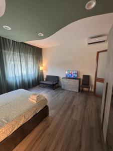 a bedroom with a bed and a couch and a tv at Le due dimore del Baluardo in Novara