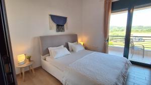 a bedroom with a white bed and a balcony at Elthea Villa in Skala Fourkas
