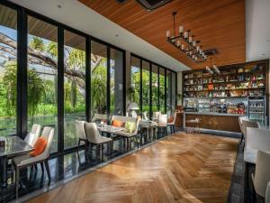 a restaurant with tables and chairs and large windows at V Villas Hua Hin - MGallery Collection in Hua Hin