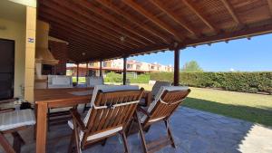 a patio with a wooden table and chairs under a roof at Elthea Villa in Skala Fourkas