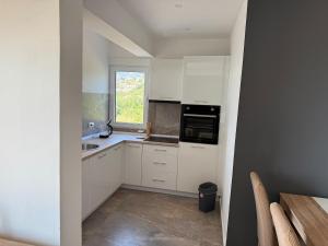 a kitchen with white cabinets and a window at Ninas Seaview Apartment in Bar