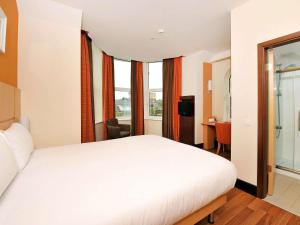 a bedroom with a large white bed and windows at ibis Belfast Queens Quarter in Belfast +36 photos
