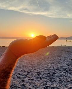 a hand pointing at the sunset on the beach at Bnb Bouveret in Port-Valais