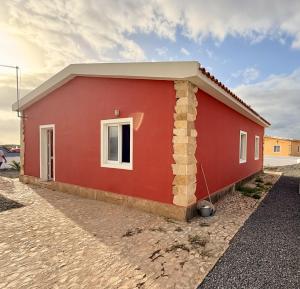 a red house with a white window on the side at Ocean Pearl Beach House in Morro
