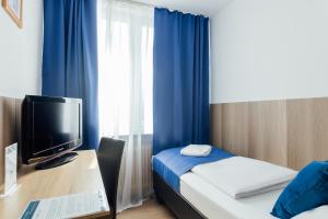 a room with a bed and a desk with a television at Hotel Hanseat Hamburg - Free Parking in Hamburg