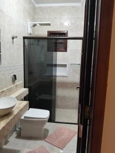 a bathroom with a toilet and a glass shower at Quarto em Foz, ótima localização em casa familiar in Foz do Iguaçu +3 photos