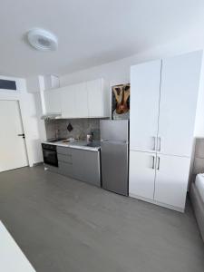 a kitchen with white cabinets and a refrigerator at Rei Apartment 2 in Shëngjin