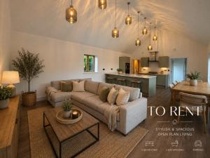 a living room with a couch and a kitchen at Blackberry Barn in Baltonsborough