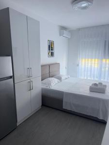 a white bedroom with a bed and a refrigerator at Rei Apartment 2 in Shëngjin