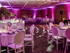 a banquet hall with white tables and chairs and purple lighting at Hotel de la Cité Carcassonne - MGallery Collection in Carcassonne +166 photos