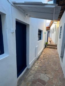 an alley with a blue door on a white building at Suite Simples PRIVATIVA in Diamantina