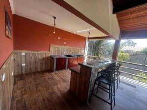 a kitchen with red walls and a bar with stools at Recanto Praia do Sargi in Uruçuca +28 photos