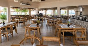 an empty restaurant with wooden tables and chairs at Mia Reef Isla Mujeres - All Inclusive Resort in Isla Mujeres