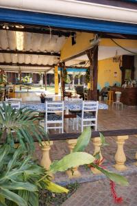 a patio with white chairs and tables in a restaurant at Pousada dos Pescadores in Bertioga