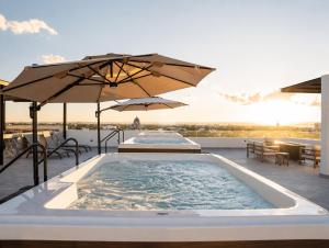 a hot tub on a patio with umbrellas at Brisamar La Paz- Terraza Vista al Mar - Cerca del Malecon in La Paz