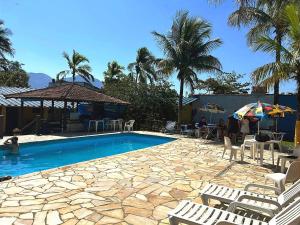 a pool with chairs and an umbrella and palm trees at Pousada dos Pescadores in Bertioga