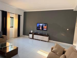 a living room with a couch and a tv on a wall at Oikos Residencial in Chimoio