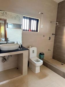 a bathroom with a sink and a toilet and a shower at Oikos Residencial in Chimoio
