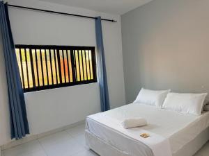 a white bed in a room with a window at Oikos Residencial in Chimoio
