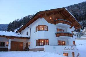 a large white house with a wooden roof in the snow at Landhaus Winkl in Ischgl