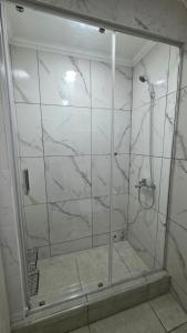 a bathroom with a shower with white marble walls at VMV Departamento in Río Grande
