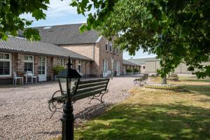 a park bench and a street light in front of a building at Hof van Alexander Boutiquehotel in Renesse