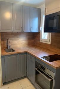 a kitchen with gray cabinets and a sink and a microwave at Clairbois in Gérardmer