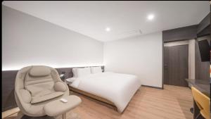 a white bedroom with a bed and a chair at HOTEL lantana in Tudomi