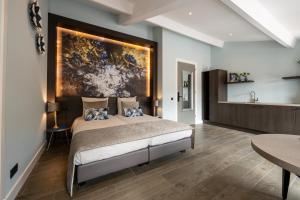 a bedroom with a bed with a painting on the wall at Hof van Alexander Boutiquehotel in Renesse