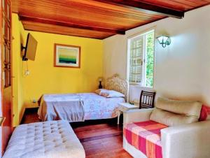 a bedroom with a bed and a couch at Pousada dos Chalés - Araras in Araras Petropolis