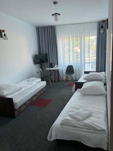 a hotel room with three beds and a desk at Noclegi Flauta in Mielno
