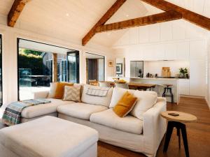a living room with a white couch and a kitchen at Blackpool Boathouse - Stay Waiheke in Oneroa