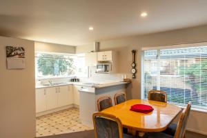 a kitchen and dining room with a wooden table and chairs at Handy Location, Ocean & Mountain Views, Close to Park - KK96845 in Kaikoura