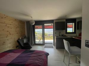 a bedroom with a bed and a kitchen with a view at Au Chant des Grillons - studio ensoleillé en Gruyère in Estavannens-Dessous
