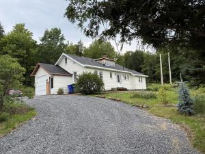 a white house on a gravel road at Le Highwater - Cabin in Mansonville