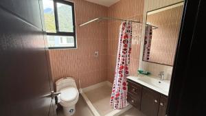 a bathroom with a toilet and a sink and a shower curtain at Volcán Suits in Baños