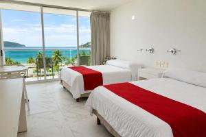 two beds in a room with a view of the ocean at We Hotel Acapulco in Acapulco +59 photos