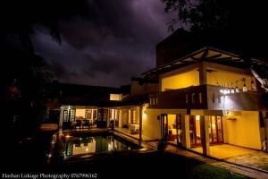 a house with a pool in front of it at night at Serendipity Lake Villa in Panadura +6 photos