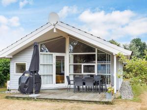 a house with a deck with chairs and an umbrella at 6 person holiday home in Væggerløse-By Traum in Bøtø By