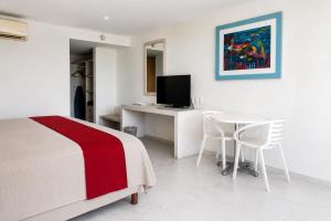 a bedroom with a bed and a table and a television at We Hotel Acapulco in Acapulco