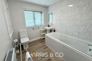 a white bathroom with a tub and a sink at Upper Marsh Apartment in Thornton